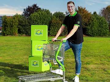 Een man met een Raiffeisen-winkelwagen op een grasveld.